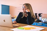 Woman leans on her arm while in front of a laptop