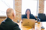 Girl at a desk talking to a man across the table