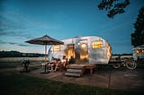 A couple relaxes at dusk in front of their camper