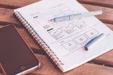 Notebook and an iphone with design wireframes