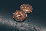 Two pence coins on a scratched black surface