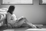 Girl sitting on floor reading a book.