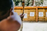 A person aiming an arrow at several targets.