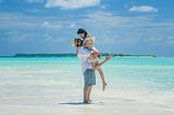 A wide shot of a couple on a beach in the Maldives, one of the best honeymoon destinations in Asia