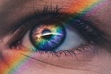 This picture shows the closeup of one eye with a rainbow running through it.