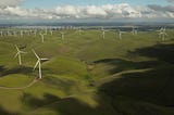 A shot of a wind farm with lush, green meadows.