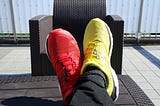 someone wearing different color sneakers, red on one foot, yellow on the other.