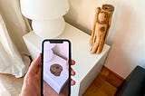 A virtual object that appears on a smartphone screen that takes pictures of a white desk with nothing.