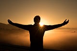 Success: Person on mountain top embracing sunset