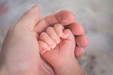 A baby’s hand lying in an adult hand.