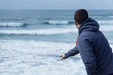 Man throwing rock into ocean