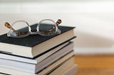 a stack of books with a pair of glasses on top