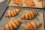 eight golden brown croissants on two baking sheets