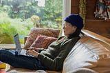 An image of a person sitting on a couch and using their Laptop.