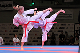 Two women kicking during a karate tournament