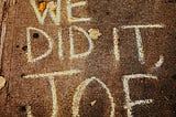 With chalk on a street’s sidewalk, it is written,” We Did It, JOE