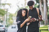 A black man and woman checking out each other's dating profile on FaithMatch