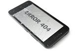 A close-up photograph of a black smartphone lying face-up with a severely cracked screen. The text ‘ERROR 404’ is clearly displayed on the fractured display, isolated on a clean white background.