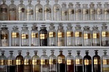 Photo by Matt Briney of many glass medicine bottles lined up across three shelves.