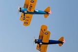 Mickey Markoff 2024 — Photo of U.S. Army Stearman planes, yellow and blue with red white and blue tails flying in sky