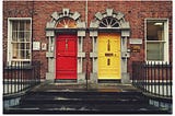 Row housing with two doors to choose, one yellow on the right and a red one on the left.