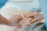 A therapist hands massaging a client’s back.