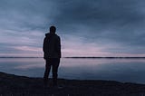 Silhouette watching the late sunset over a lake.