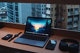 A picture of a laptop, phone, smartwatch and a window side