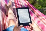 Woman sitting in a pink striped hammock reading an Kindle ebook