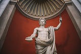 A laurel-wreathed marble statue stands in a Roman temple, holding a stick aloft in one hand, and a shell in the other