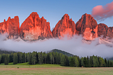 Scenic landscape of the Dolomite Mountains at sunset, with vibrant colors illuminating the peaks.