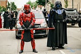 Two Star Wars cosplayers, one dressed as Darth Maul, the other dressed as Darth Vader.