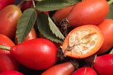 A close up of bright red rose hips, one of it being cut open