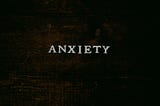 The word “Anxiety” is written across some dark-stained wood.
