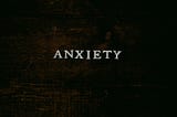 The word “Anxiety” is written across some dark-stained wood.