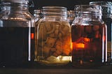 Jars of pickled vegetable with a dark background. Light is filtering through the jars with a warm tone.