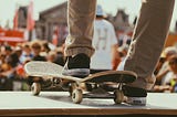 person steps on a skateboard in front of a crowd. they’re probably going to fall down a steep slope.