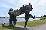 statues of giants carrying a boat ashore