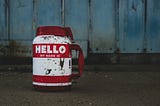 Dirty mug on the ground that has label that says “Hello my name is,” and its left blank