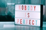 A sign that states “Nobody is Perfect”