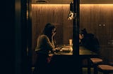 A woman looking at her phone in a dimly lit bar.