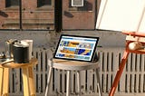 A tablet computer next to a canvas and buckets of paint.