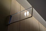 Photo of Washroom Sign of a generic woman shape and man shape. Photo by Franck V. on Unsplash