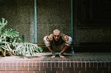 Man squatting in an advanced yoga pose, confronting the camera