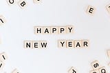 A white surface on which scrabble tiles have been arranged to spell out Happy New Year.