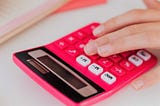Fingers over a pink calculator