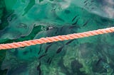 Tan colored rope over emerald green water