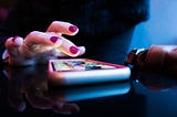 A girl with manicured nails tapping a phone screen