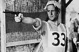 Man in a sports uniform aims a pistol at a target