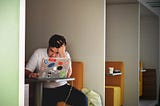 An overworked employee sitting on a table with a laptop.